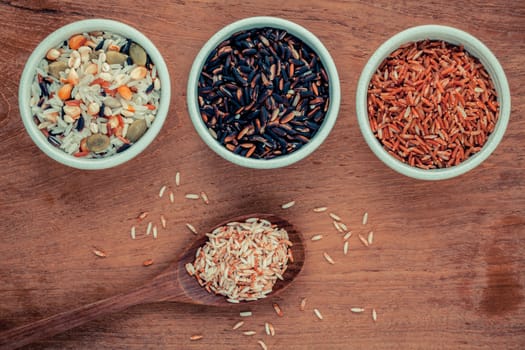 Mixed Whole grain Traditional Thai rice in the spoon and bowl best rice for healthy and clean food on teak wood background.