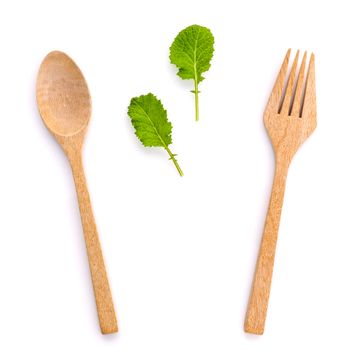 Healthy food concept fresh organic green leaves with wooden fork and spoon isolated on white background cutout .