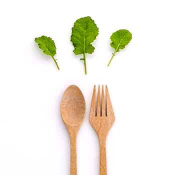 Healthy food concept fresh organic green leaves with wooden fork and spoon isolated on white background cutout .