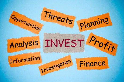Invest concept word on torn paper color on blue background. business concept.