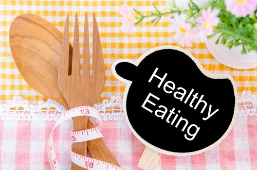 Healthy Eating wood tag and wood spoon, on beautiful fabric background.