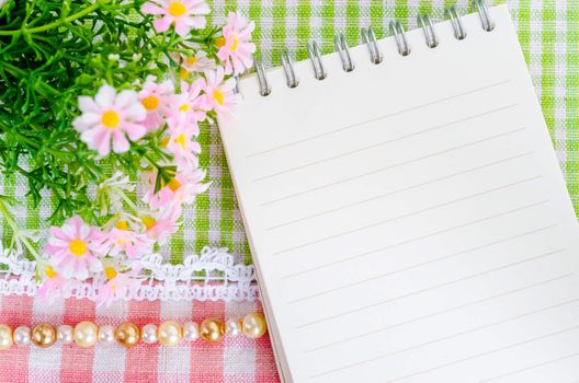 Empty notebook with beautiful flower on beautiful fabric background.