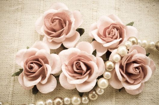 Vintage pink rose and Pearl Necklace on fabric background. Love concept.