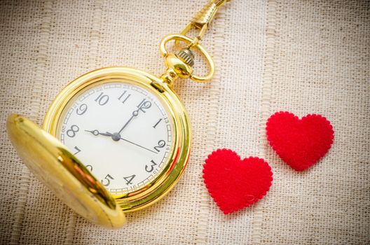 Gold pocket watch and red heart on sack background. Love concept.