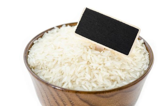 Raw rice and black wooden tag in wooden bowl on white background for your text.
