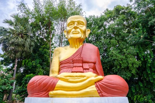 Big Buddha statue and big trees in garden.