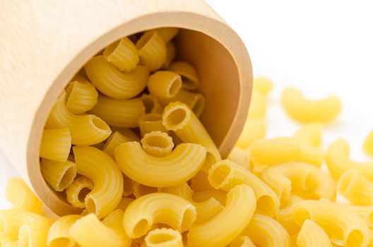 Raw dry elbow macaroni. Italian Pasta raw food in wooden bowl on white background.