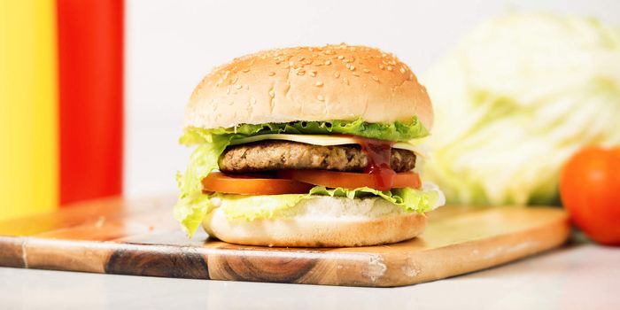 Hamburger with cheese and ingredients with a white background and timber board.