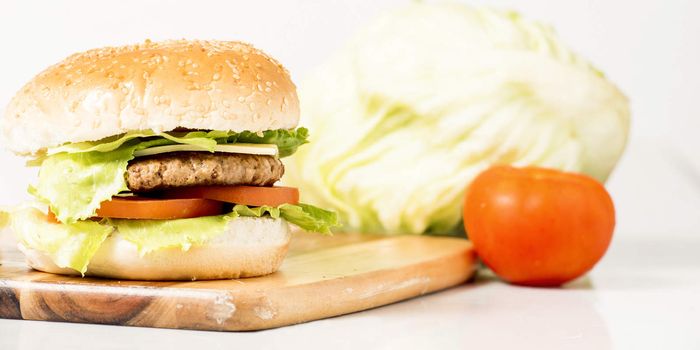 Hamburger with cheese and ingredients with a white background and timber board.