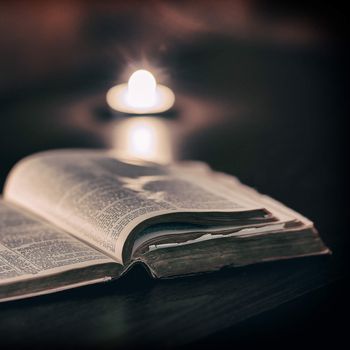 Bible with candles in the background. Low light scene.