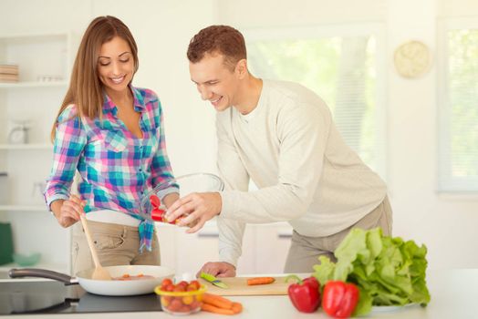 Beautiful young couple cooking healthy meal in the domestic kitchen. 