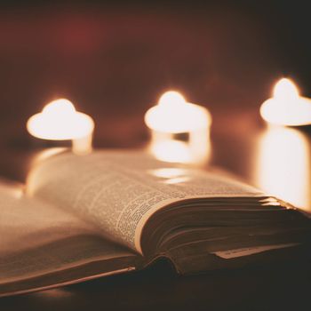 Bible with candles in the background. Low light scene.