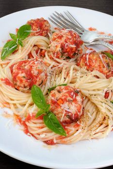 Pasta in tomato gravy with meatballs sprinkled Parmesan and basil