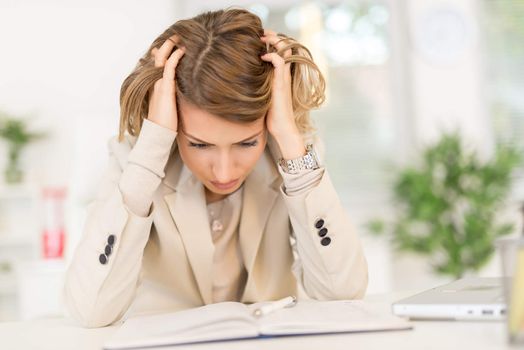 Frustration young businesswoman sitting in the office and looking at document.