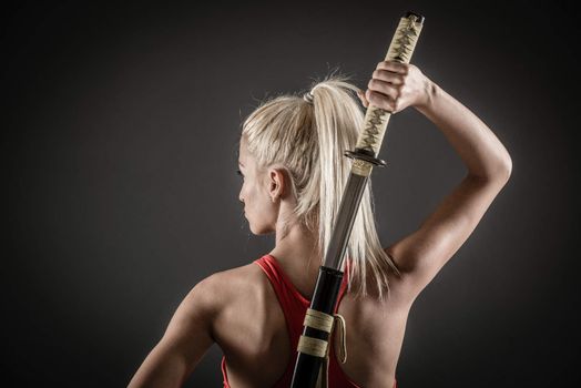 Pretty girl with a serious expression on her face drawing katana. 