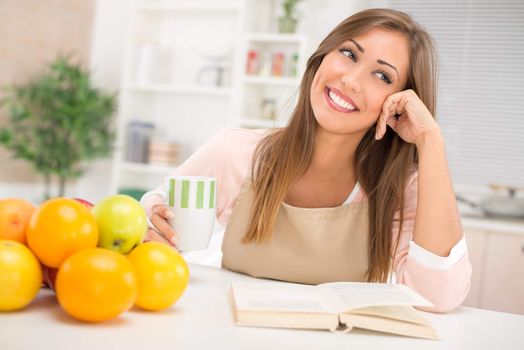 Beautiful young woman in the kitchen drinking coffee and thinking.