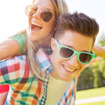 holidays, vacation, love and friendship concept - smiling teen couple in sunglasses having fun in summer park