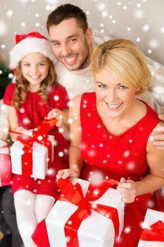 christmas, holidays, happiness and people concept - smiling family in santa helper hats with many gift boxes at home