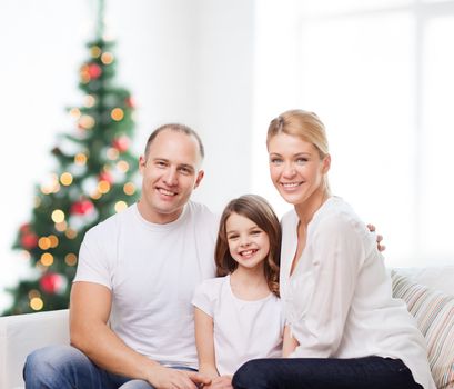 family, childhood, holidays and people - smiling mother, father and little girl over living room and christmas tree background