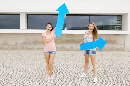 Teenage students holding blue arrows and pointing in diferent directions