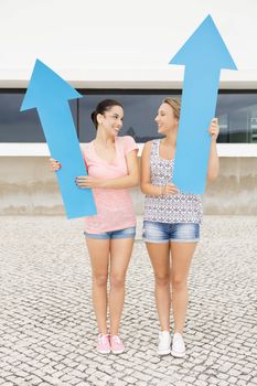 Teenage students holding blue arrows and pointing in diferent directions