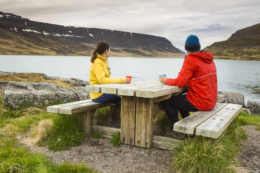 A couple drinking tea close to a beautiful lake