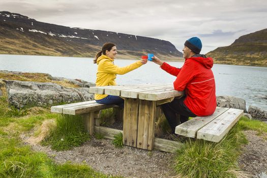 A couple drinking tea close to a beautiful lake