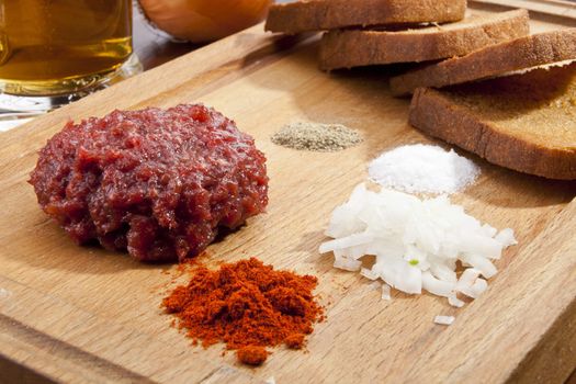 Steak tartar with the fried bread on the wooden trencher