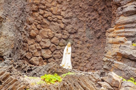 Praying Madonna in front of rock wall in Ribeira da Janela, Madeira, Portugal