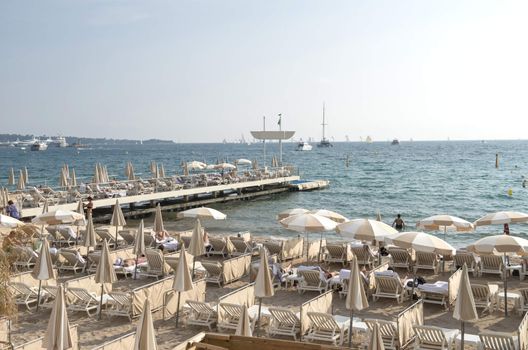 Cannes, France - May 6, 2013: People on the beach in Cannes.  The famous beach on the Croisette, known for its cinema festival. People are sun bathing, swiming and resting 8 mounth in the year.