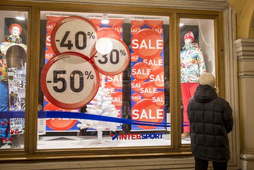 Retail shop window with model mannequins and sale sign.