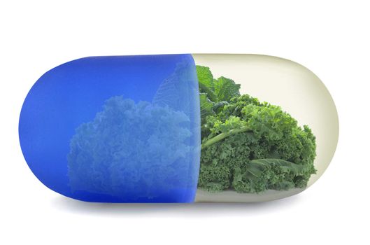 Close up of a vitamin pill with green vegetables including kale, cabbage and lettuce