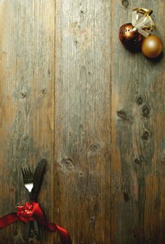 Wooden  background menu with cutlery tied in red ribbon and xmas baubles 