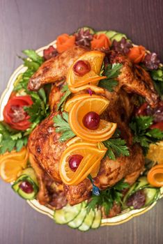 Whole roasted chicken with vegetables and fruits on wooden table
