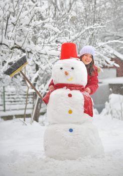 girl with snowman in garden on a winter day