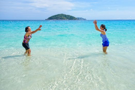 Mother and daughter wear a swimsuit playing in the blue sea near the beach with happiness during summer at Koh Miang Island, Mu Ko Similan National Park, Phang Nga province, Thailand