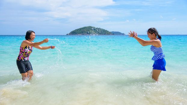 Mother and daughter in a swimsuit playing on the blue sea near the beach with happiness during summer at Koh Miang Island, Mu Ko Similan National Park, Phang Nga, Thailand, 16:9 widescreen