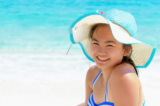 Girl in a blue swimwear sitting a happy on the beach with the sea as background during summer at Koh Miang Island, Mu Ko Similan National Park, Phang Nga province, Thailand