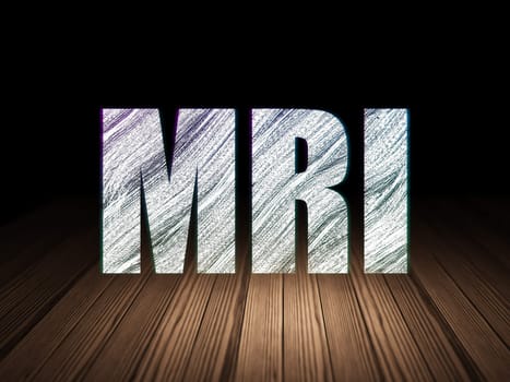 Healthcare concept: Glowing text MRI in grunge dark room with Wooden Floor, black background