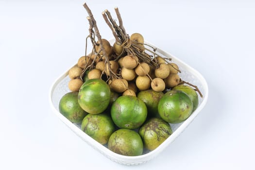 Bunchs of longan and oranges in white basket  on white background