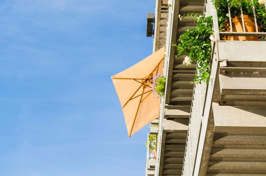 View from bottom looking up at the balcony with parasol against the light.