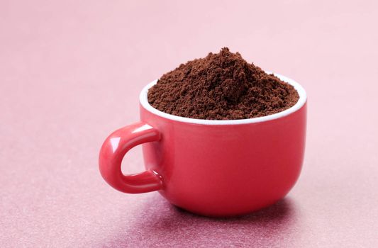 Heap of freshly ground coffee in a red cup