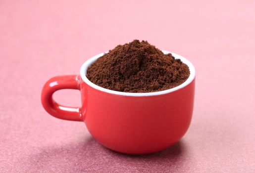 Heap of freshly ground coffee in a red cup