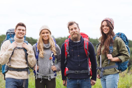 adventure, travel, tourism, hike and people concept - group of smiling friends standing with backpacks