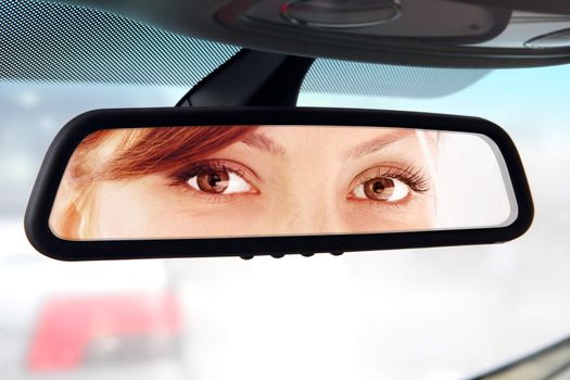 woman sits on driver's seat and Looks in the rear-view mirror