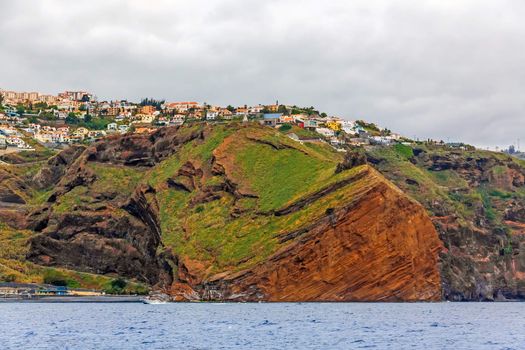 Cliff coast off town Canico, Madeira - offshore view, dramatic sky, sunset