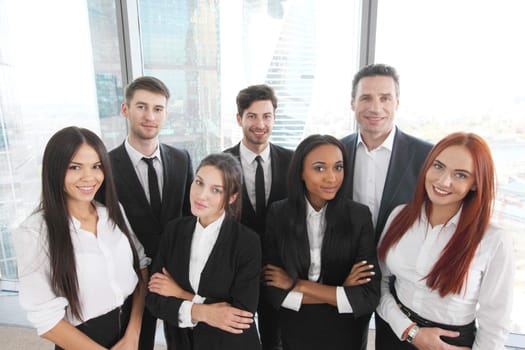 Portrait of business team of men and women in office with view on skyscrapers