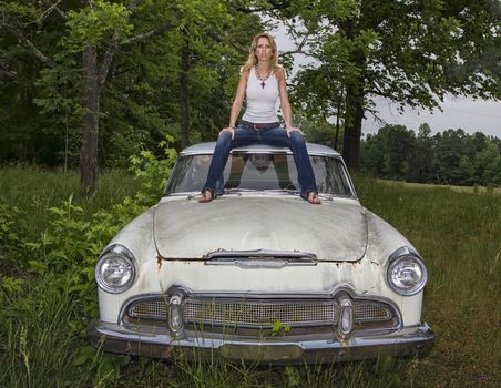 A model posing outside an old worn out vehicle