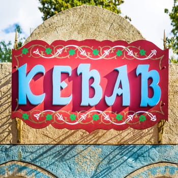 Sign decorated and painted with raised letters that form the word "kebab".