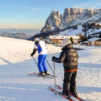 ORTISEI, ITALY - CIRCA DECEMBER 2012: Father and son skiing on the snowy slopes of the Alps.